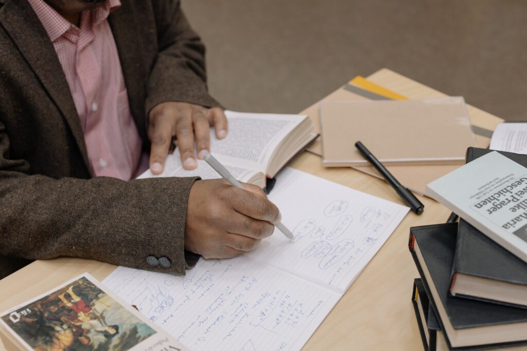 Person in Pink Long Sleeve Shirt Writing on White Paper